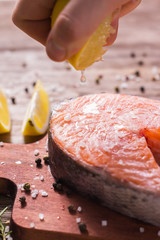 Squeezing fresh lemon juice on the fillets of fish. Cooking salmon steak.