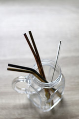 Reusable metal straws and cleaner in a glass jar. Selective focus.