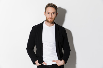 Image of unshaven confident man in jacket posing and looking at camera
