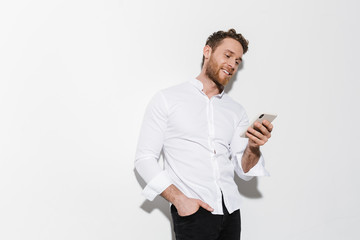 Image of handsome joyful man in shirt typing on cellphone and smiling