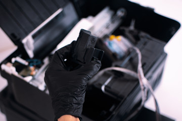 repairman printer hand holding ink cartridge for inkjet printer. Professional printer maintenance concept Technical assistance in office hardware Continuous ink system repair Copy space
