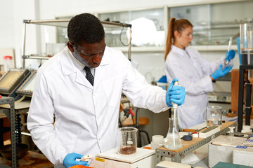 Focused man lab technician in gloves working with reagents and test tubes