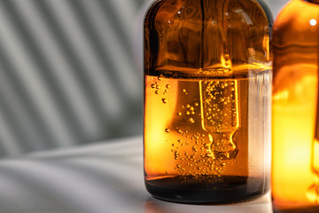 Brown glass bottles with oily skincare serum close up on white table