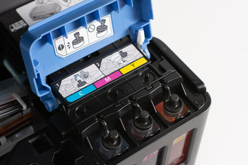 Up close, ink tanks from a printer displaying CMYK Cyan, Magenta, Yellow and Key colors, continuous...
