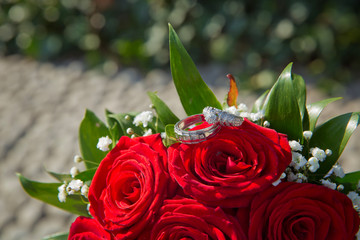 A bouquet of roses for a wedding. Bride and groom rings on a red wedding bouquet.