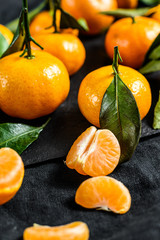 Tangerines (oranges, mandarins, clementines, citrus fruits) with leaves. Black background. Top view