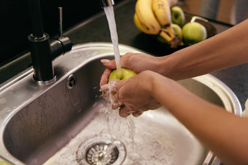 cropped view of girl washing fruits in washbasin during quarantine