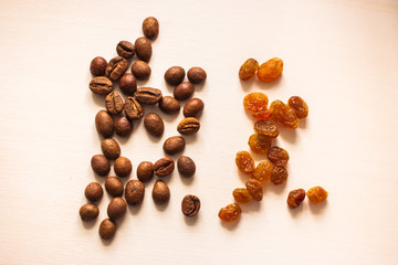 Coffee beans and light raisins on white background. Roasted coffee and raisin. Sweet ingredients. Aroma seeds. Natural ingredients. Dry food concept.