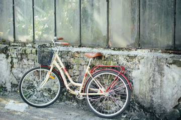 Yellow bicycle is standing in garden, against background of an old brick building. Сoncept of loss, loneliness.
