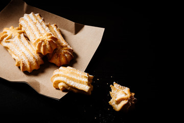Shortbread cookies with icing sugar on a paper plate. Dark background.