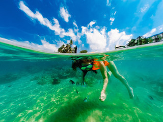 snorkelling girl in mask feeds fish underwater 