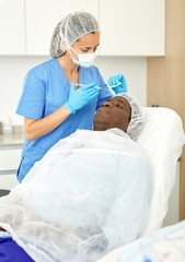 Man client and doctor during beauty facial injections in medical esthetic office