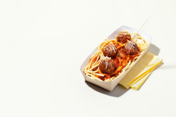 Italian spaghetti and meatballs with tomato sauce in takeaway packaging box on white background with shadow.Restaurant food delivery concept