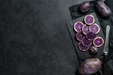 Raw sliced purple potatoes. Black background. Top view. Space for text