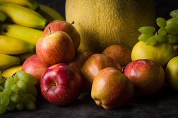 fruits cabbage banana melon grape orange apples pear a dark background. health vegetarianism