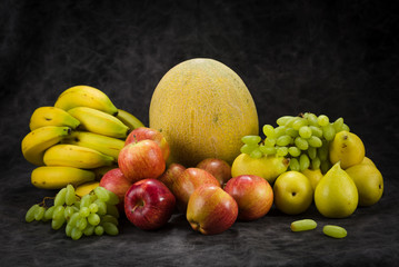 fruits cabbage banana melon grape orange apples pear a dark background. health vegetarianism
