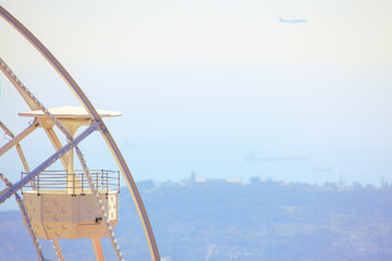 cabin of white ferris wheel with coastal view at background