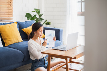 Obraz na płótnie Canvas Young Asian businesswoman work at home and virtual video conference meeting with colleagues business people, online working, video call due to social distancing at home office