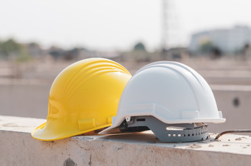 White and yellow helmet placed on the construction site. - obrazy, fototapety, plakaty