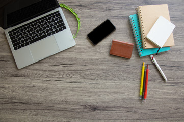 A top view of a business desk that includes pens, notebook, business card bag, computer laptop and smartphone on a wooden table to connect with others in the digital technology world with copy space