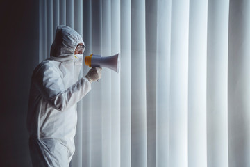 Doctor in hazmat suit shouting with megaphone