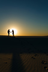 Fototapeta na wymiar Newlyweds walk barefoot on the sand in the white desert