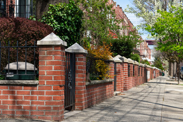 Fototapeta na wymiar Beautiful Spring Sidewalk with Brick Fences and Gardens in front of Homes in Astoria Queens New York