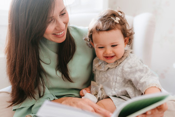 mother and little daughter read a book at home