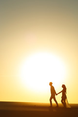 Newlyweds walk barefoot on the sand in the white desert