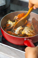 Close-up photo of human cooking salt pepper stir-fried crab