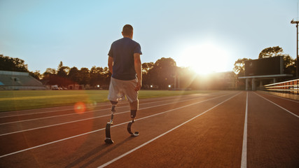 Athletic Disabled Fit Man with Prosthetic Running Blades is Walking During a Training on an Outdoor Stadium on a Sunny Afternoon. Amputee Runner Preparing for a Run. Motivational Sports Shot.