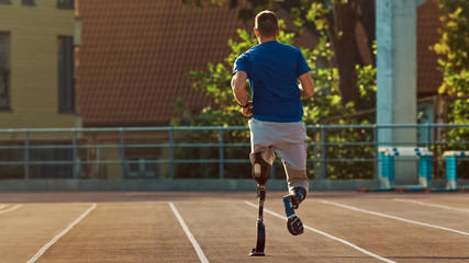 Athletic Disabled Fit Man with Prosthetic Running Blades is Training on a Outdoors Stadium on a Sunny Afternoon. Amputee Runner Jogging on a Stadium Track. Motivational Sports Shot.