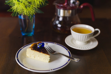 Teatime with slice of basque burnt cheesecake and cup of tea on table.
