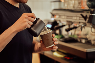 a young man pours coffee in a coffee shop