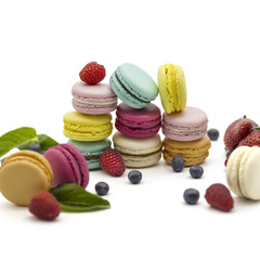 Multicolored macaroons on a white background with strawberries, raspberries, mint and blueberries