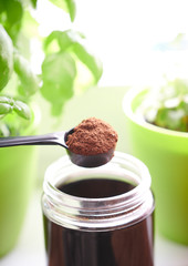 Focus on coffee powder ready for a homemade espresso and basil green in the background