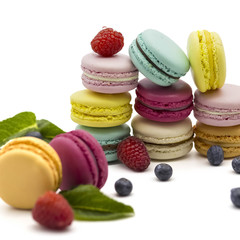 Multicolored macaroons on a white background with strawberries, raspberries, mint and blueberries