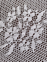 White crocheted background with flowers and leaves.