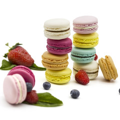Multicolored macaroons on a white background with strawberries, raspberries, mint and blueberries