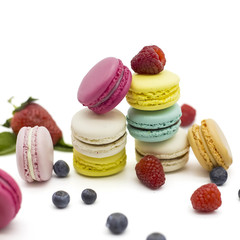 Multicolored macaroons on a white background with strawberries, raspberries, mint and blueberries