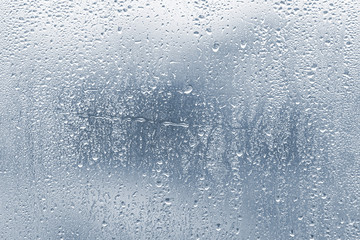 Raindrops, condensation on the glass window during heavy rain, water drops on blue glass