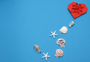 Red heart with seashells on a blue background with copy space