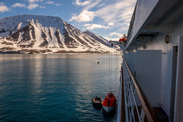 Lowering orange lifeboat to water in Arctic waters, Svalbard. Abandon ship drill. Lifeboat...