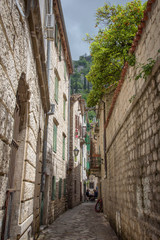Narrow street with stone facades, in Kotor, a city located in a bay of the Adriatic Sea, in Montenegro, Europe.