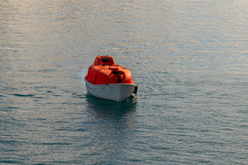 Maneuvering orange lifeboat in water in Arctic waters, Svalbard. Abandon ship drill. Lifeboat...