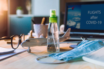 Sanitizer, face mask and airplane toy on wooden table