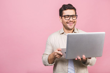 Young business man wearing glasses working using computer laptop with a smile isolated over pink background.