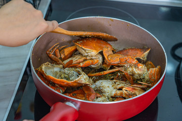 Human hand using spatula and cooking stir-fried salt pepper crab 