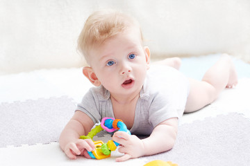 The baby s teeth are being cut. A cute kid with blue eyes is playing with toy