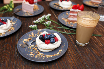 Sweet cakes with summer berries on a wooden table. Party, sweet table. Summer offer desserts in the restaurant.